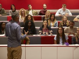 Back View Of Man Presenting To Students At A Lecture