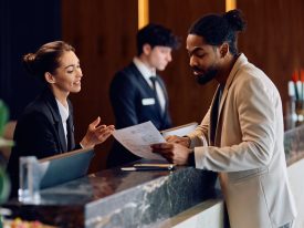 African American Man Checking In At Reception Desk In A Hotel.
