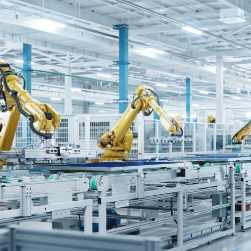 Large Production Line With Industrial Robot Arms At Modern Bright Factory. Solar Panels Are Being Assembled On Conveyor.