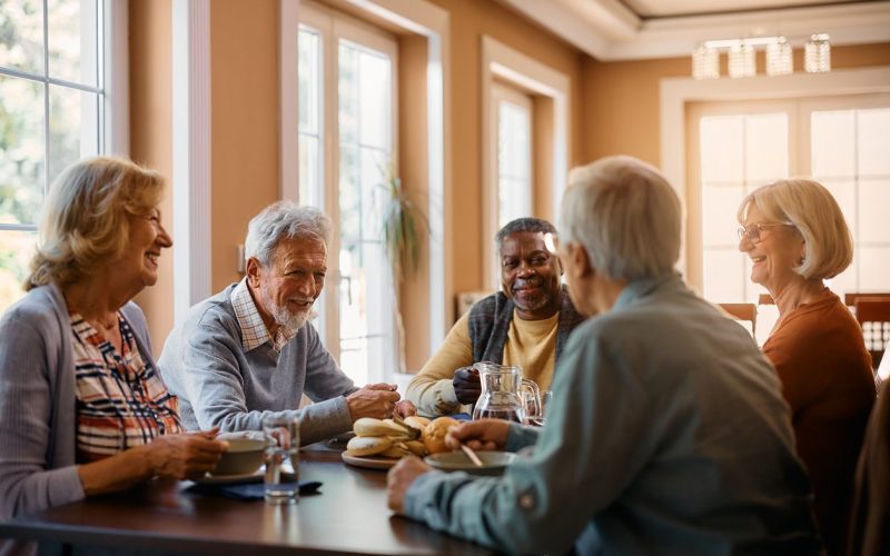 Happy Seniors Talking While Eating Lunch At Residential Care Home.