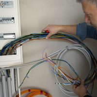 Male Electrician With Blue Jeans Shirt Works On Construction Site