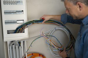 Male Electrician With Blue Jeans Shirt Works On Construction Site
