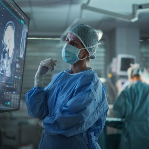 Professional Focused Caucasian Female Surgeon Reviewing Patients Brain Scans On A Large Monitor, Preparing To Lead Her T
