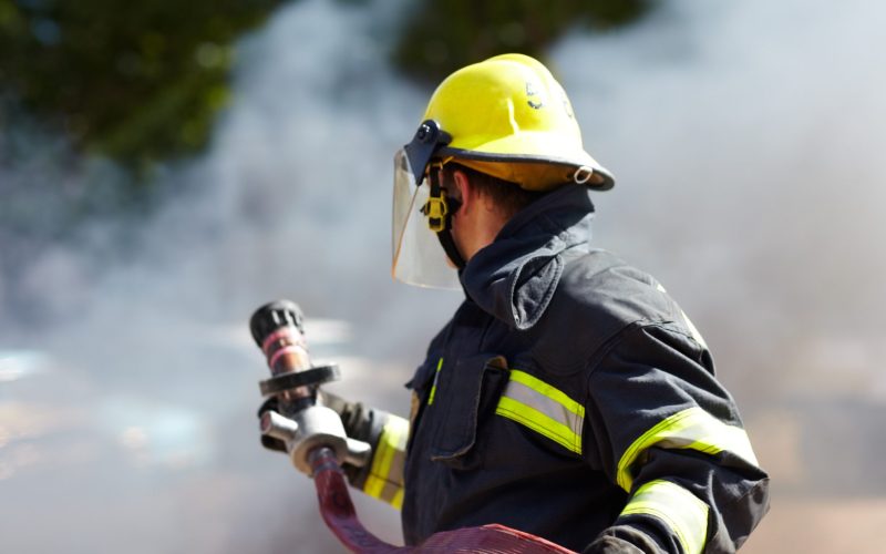 A fireman using a firehouse during a fire.
