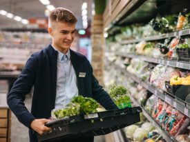 Shop Assistant Restocking The Produce Section Shelves
